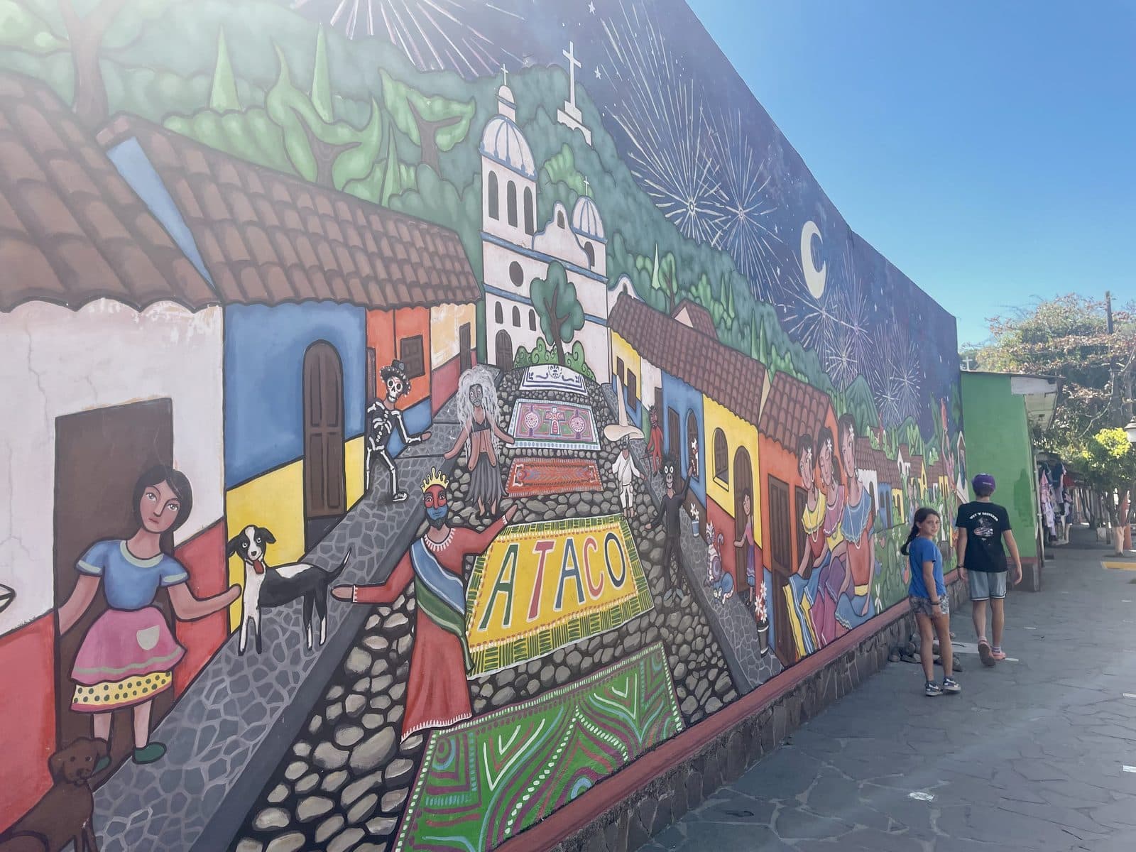 My kids exploring a colourful mural-covered street in Ataco, El Salvador, learning happens everywhere