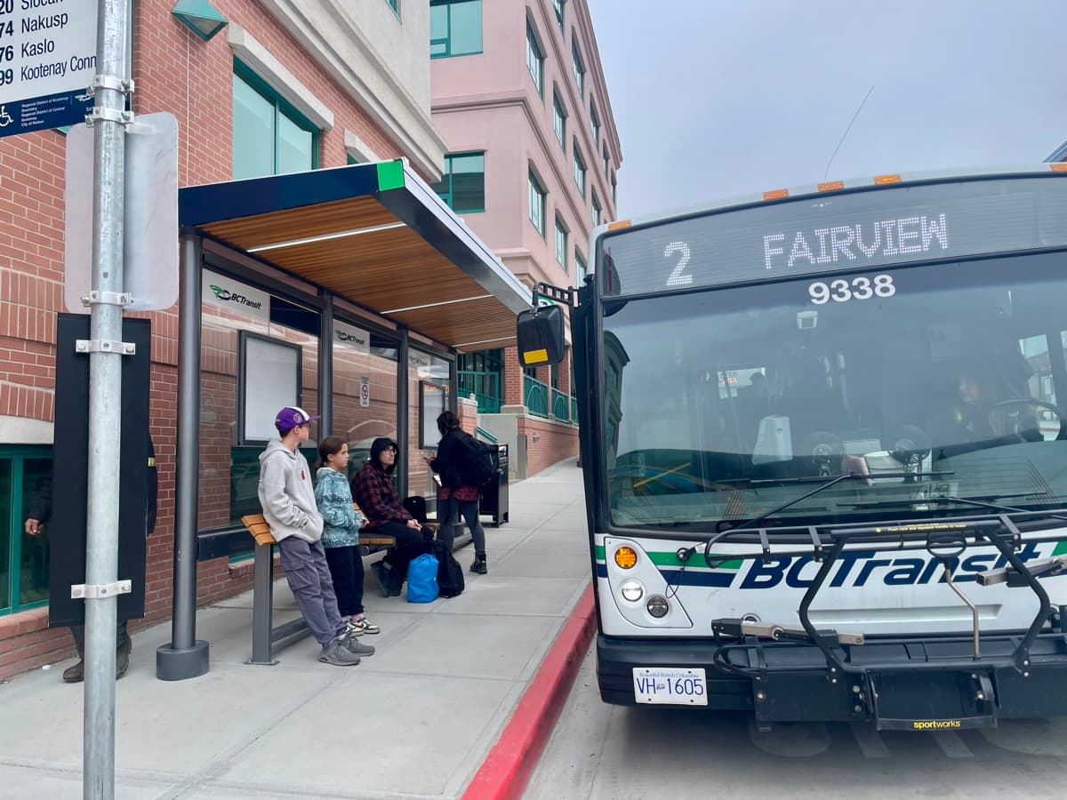 Zach and Julia waiting at a BC Transit bus stop as the city bus pulls up