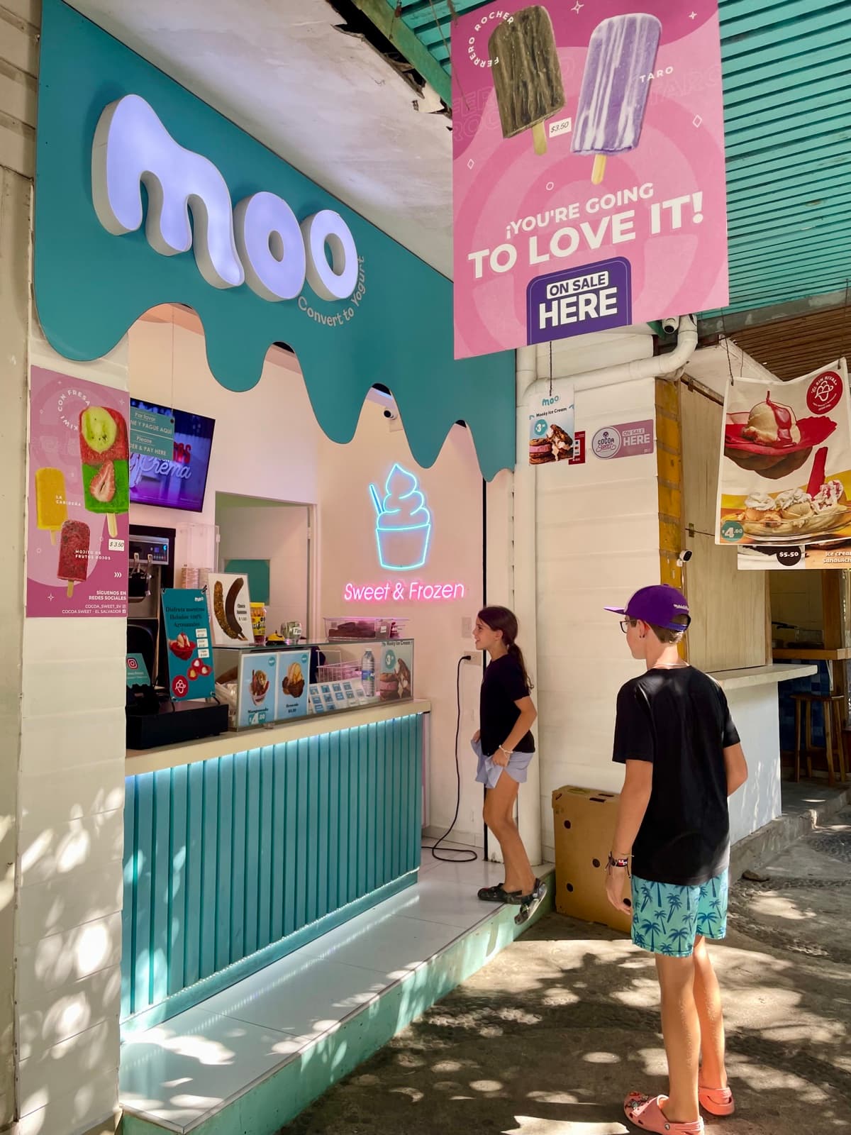 Zach and Julia ordering ice cream at a shop on their own, reading the menu, choosing, and paying