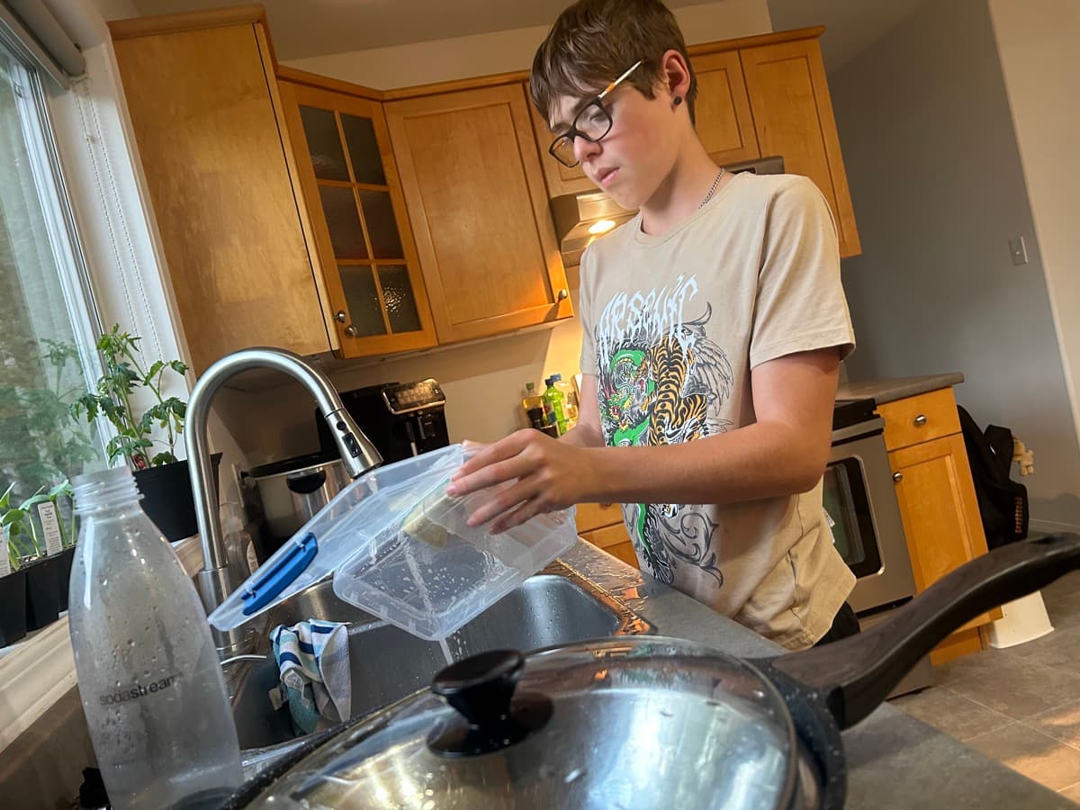 Child washing dishes independently at the kitchen sink