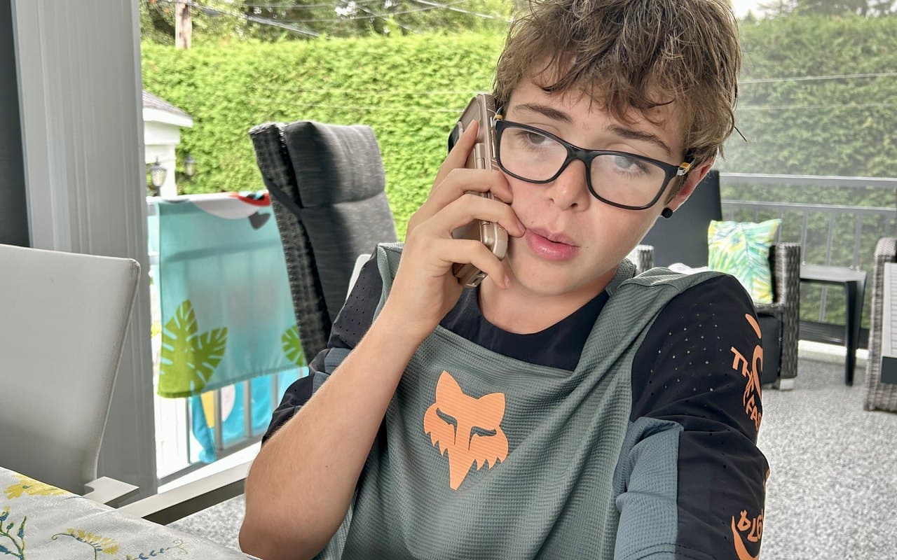 A tween making his own phone call, focused and serious, learning to communicate by doing it himself