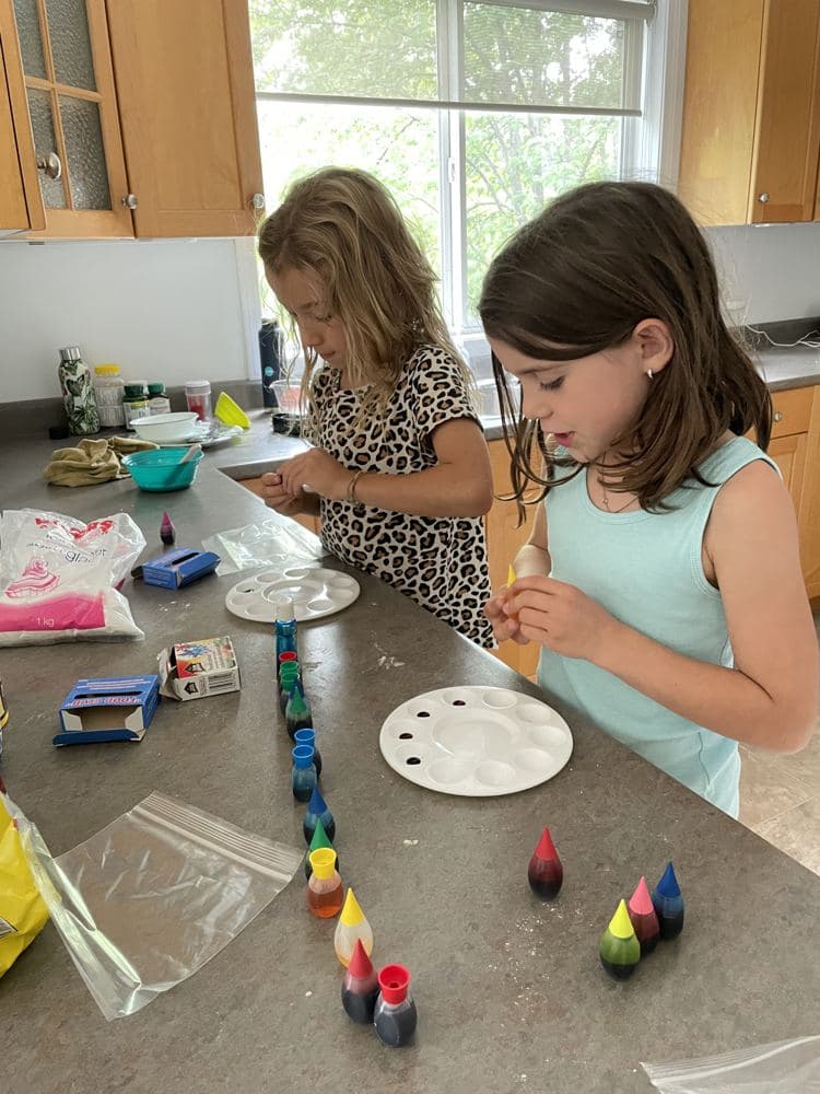 Two girls doing a colour experiment at the kitchen counter