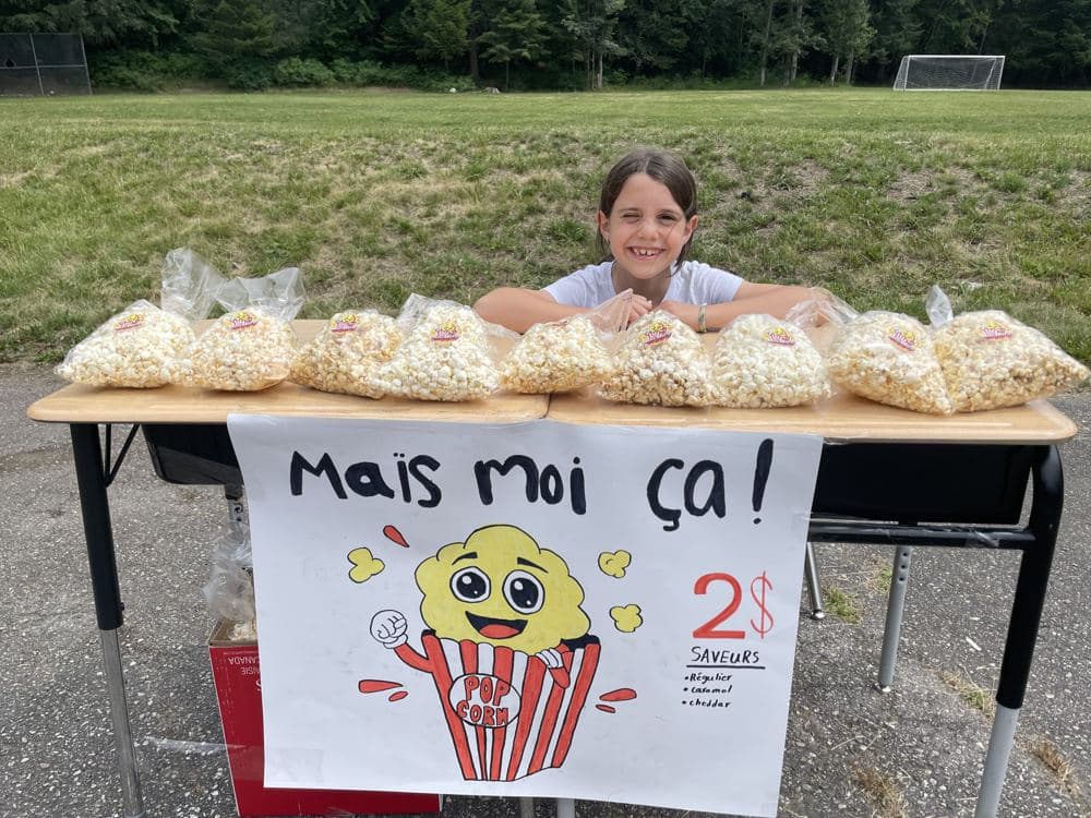 A girl selling bags of popcorn at her own stand