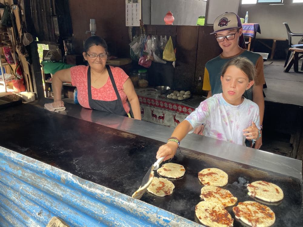 A girl cooking pupusas on a griddle