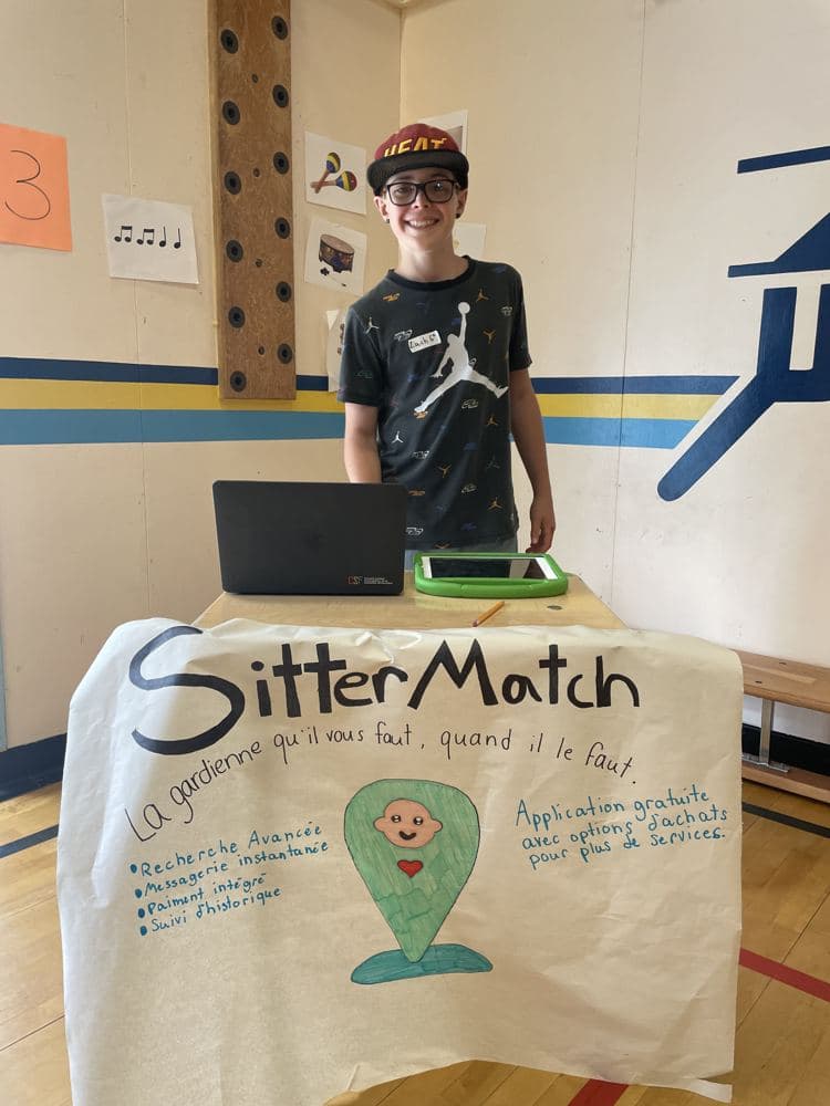 A boy standing behind his business poster at a table