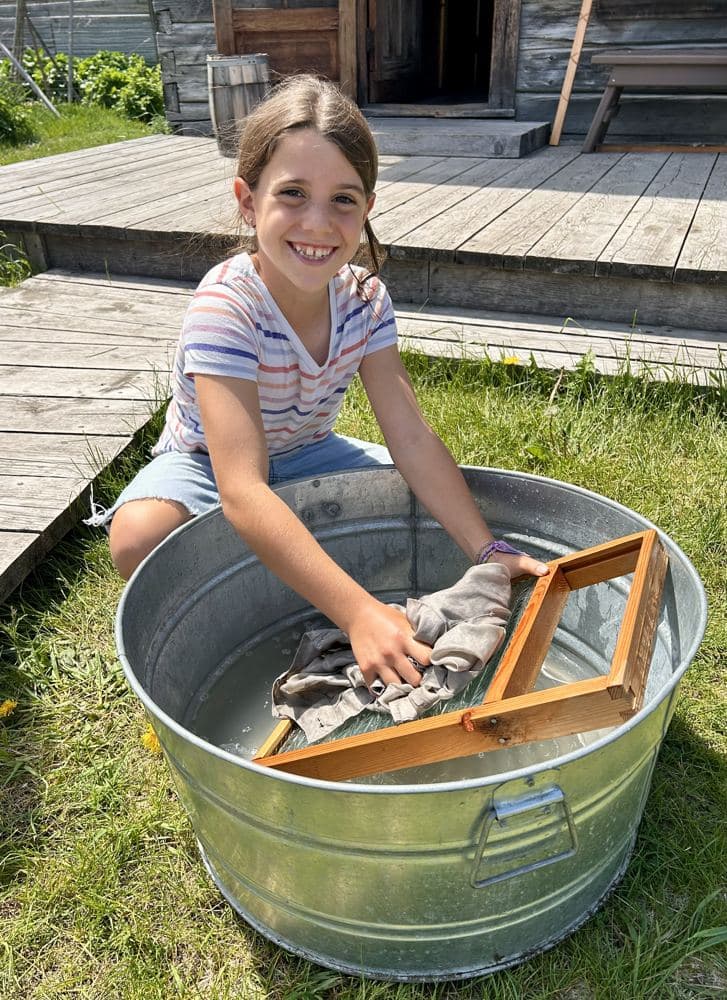 A girl washing clothes on a washboard