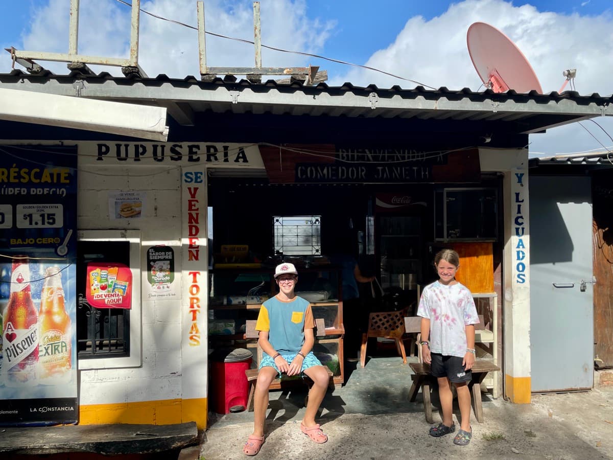 My son and daughter sitting in front of a local pupusería in El Salvador