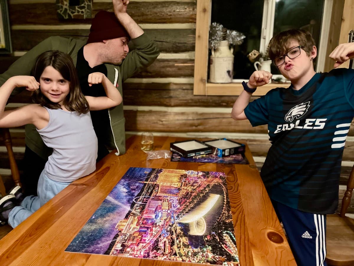 Family celebrating after finishing a complex jigsaw puzzle together in a cozy cabin