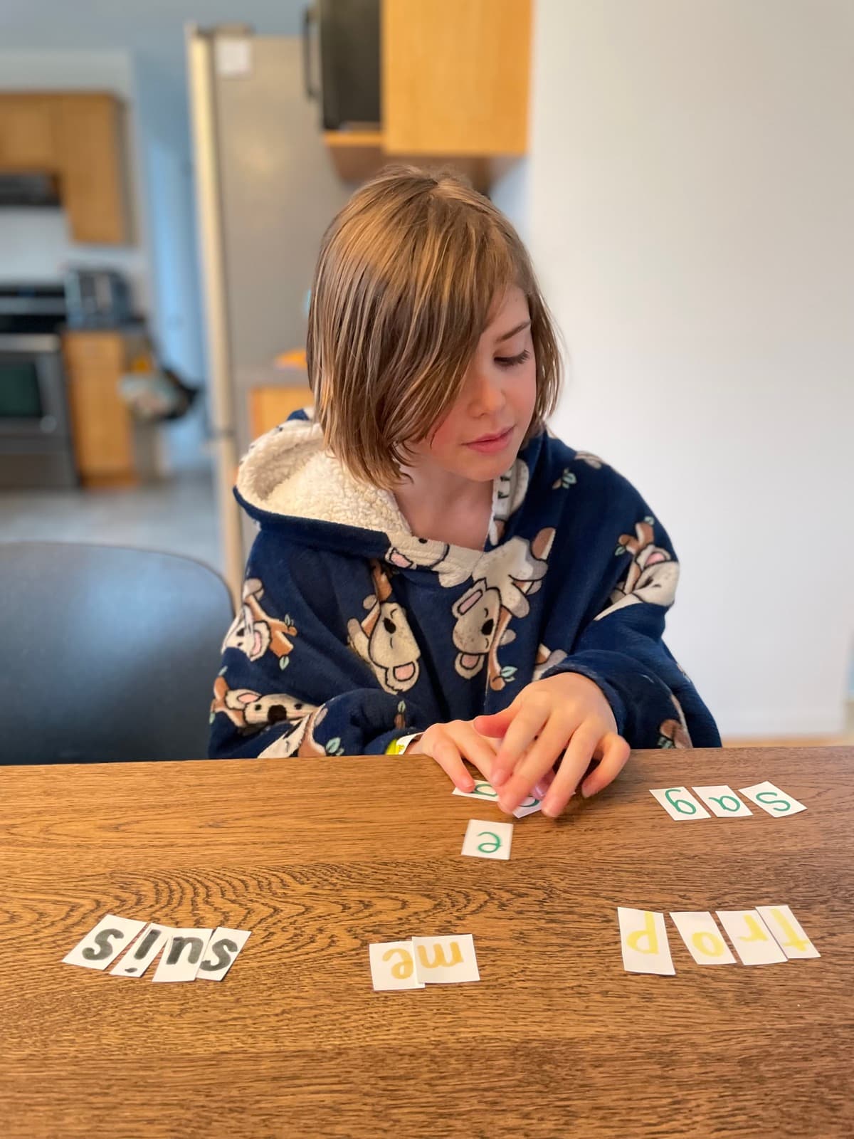 Child sorting and arranging French word cards on a table, practicing sequencing and recall