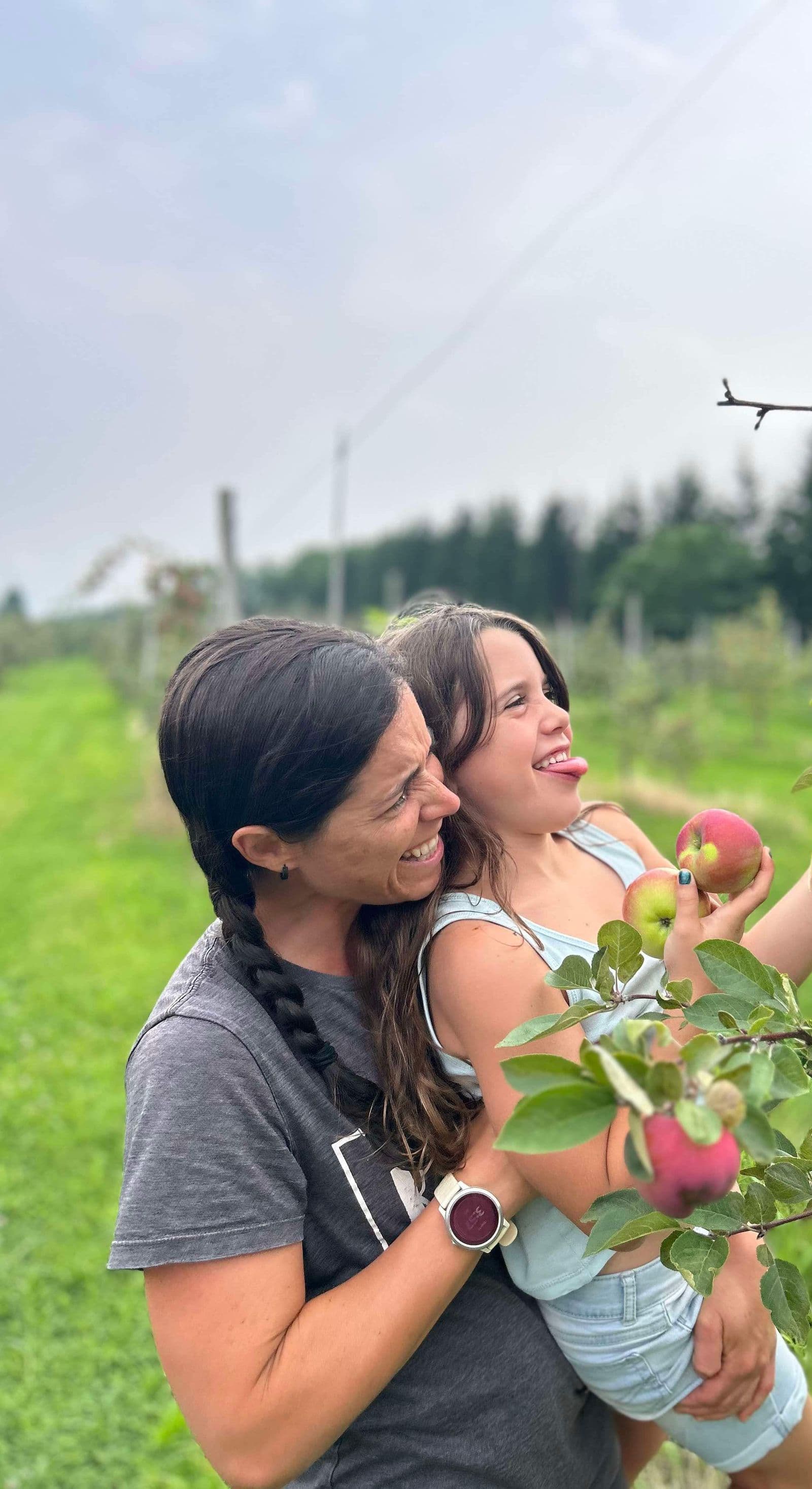 Mom and Julia laughing together while apple-picking in an orchard, the warm beginning of a year of learning side by side