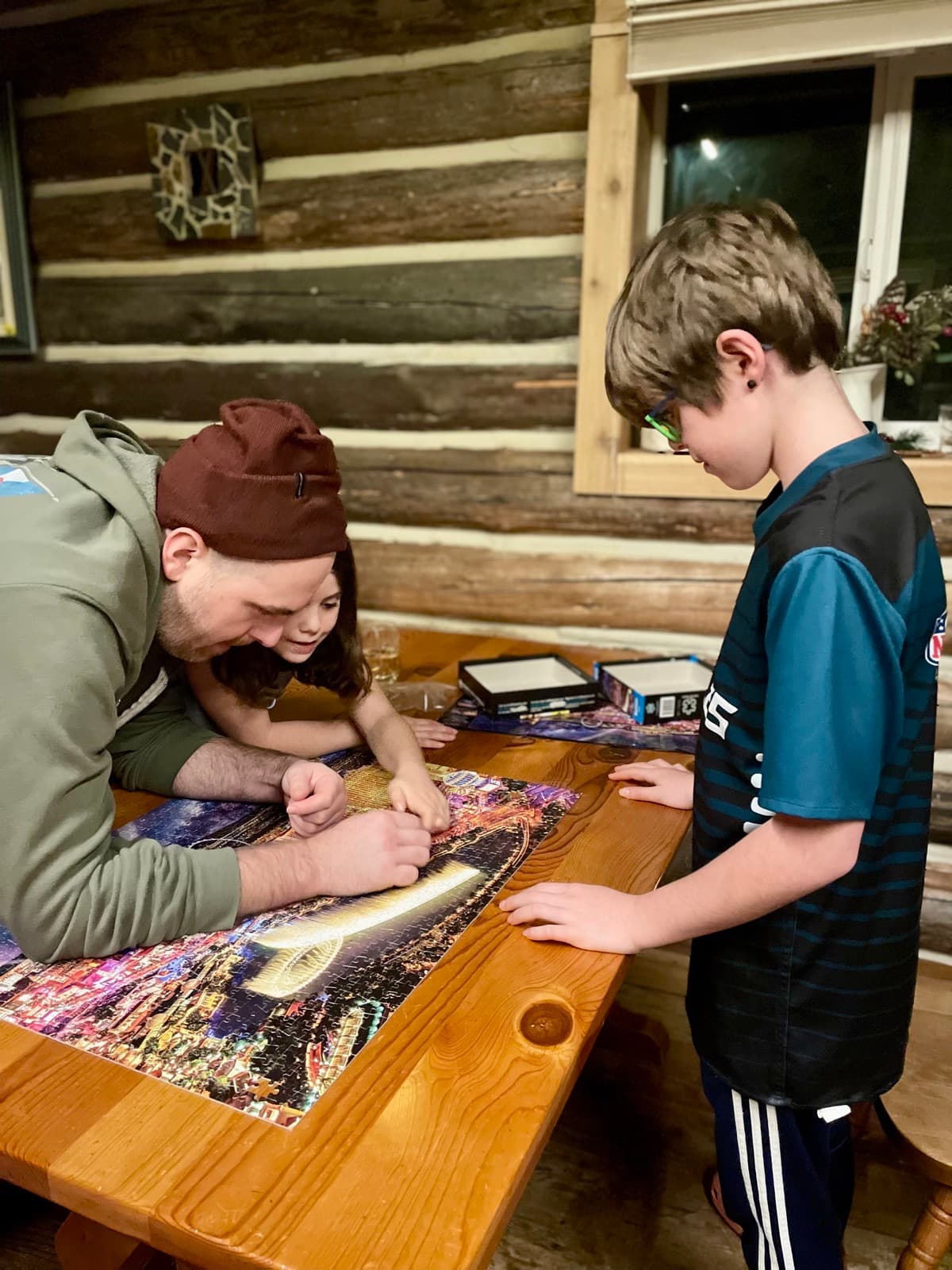 Family working on a jigsaw puzzle together at a wooden cabin table, the kind of slow shared time that holds a homeschool year together