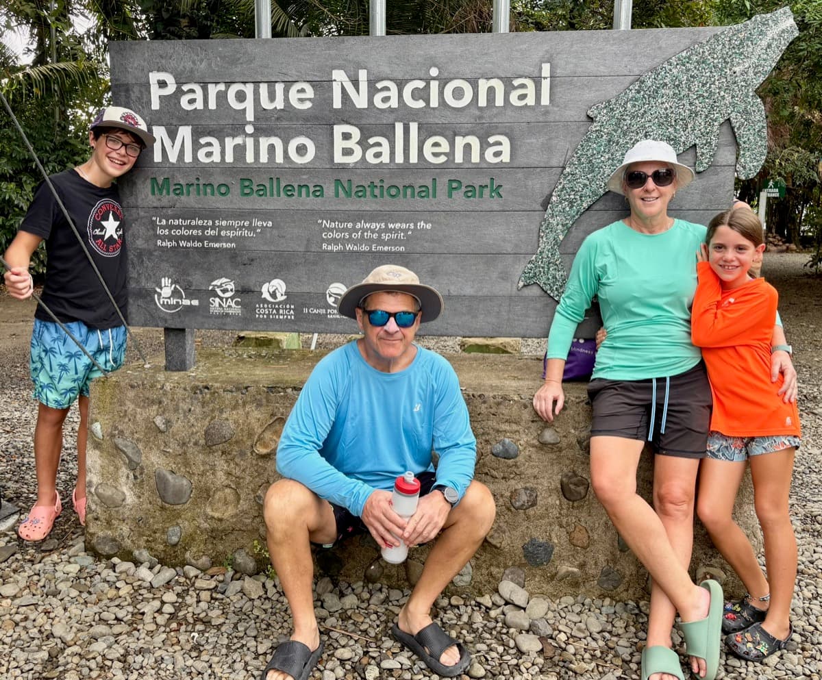 The whole family posing at the Parque Nacional Marino Ballena sign in Costa Rica