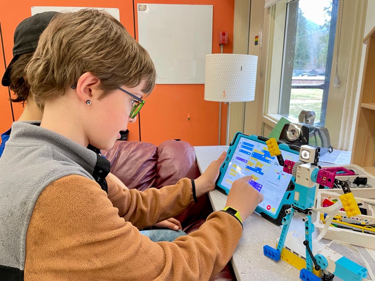 Zach programming a LEGO robot with a tablet at a maker workshop