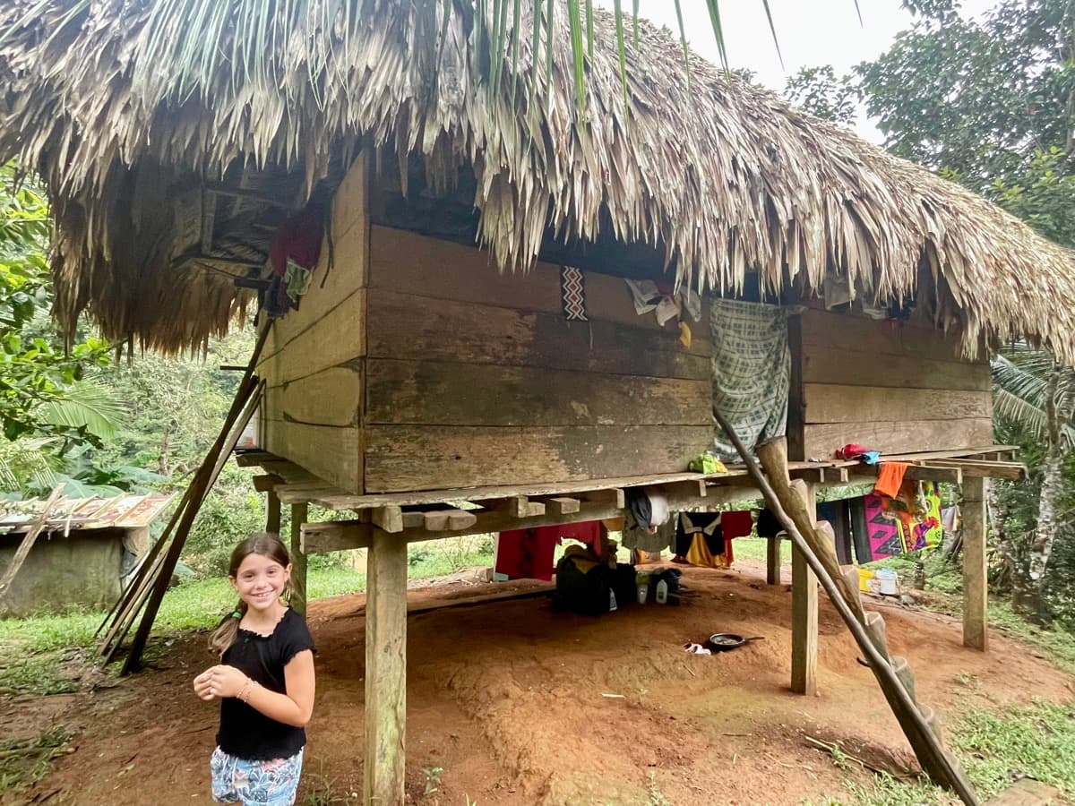 My daughter standing in front of a traditional stilted hut in an indigenous village in Panama