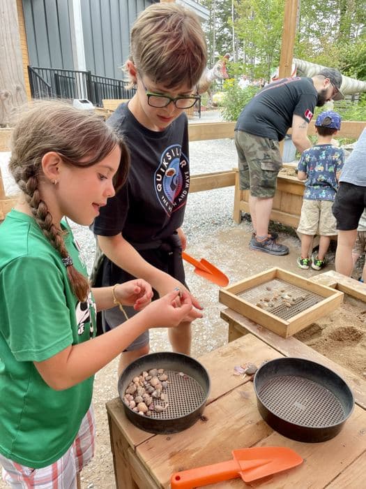 Two kids sifting through finds at an outdoor table