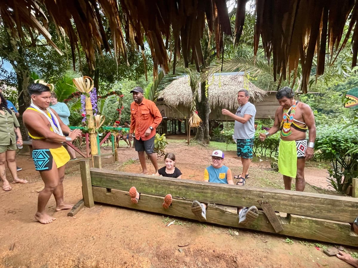 Family visiting an indigenous community in Panama, kids watching and learning from local traditions