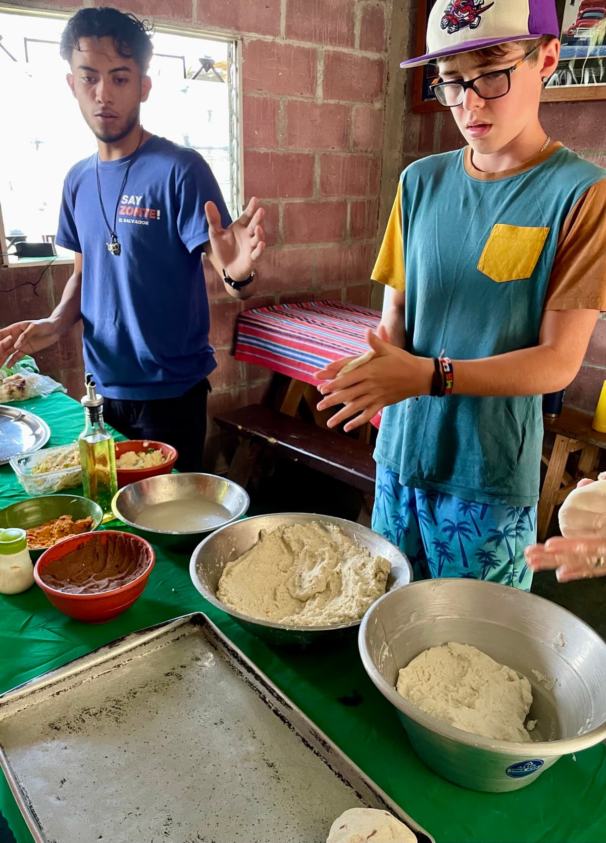 My son learning to make pupusas with a local instructor in El Salvador