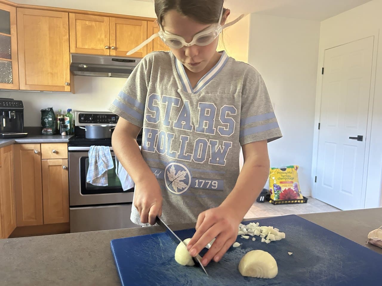 A tween confidently cutting vegetables with a real knife in the kitchen, cooking on his own