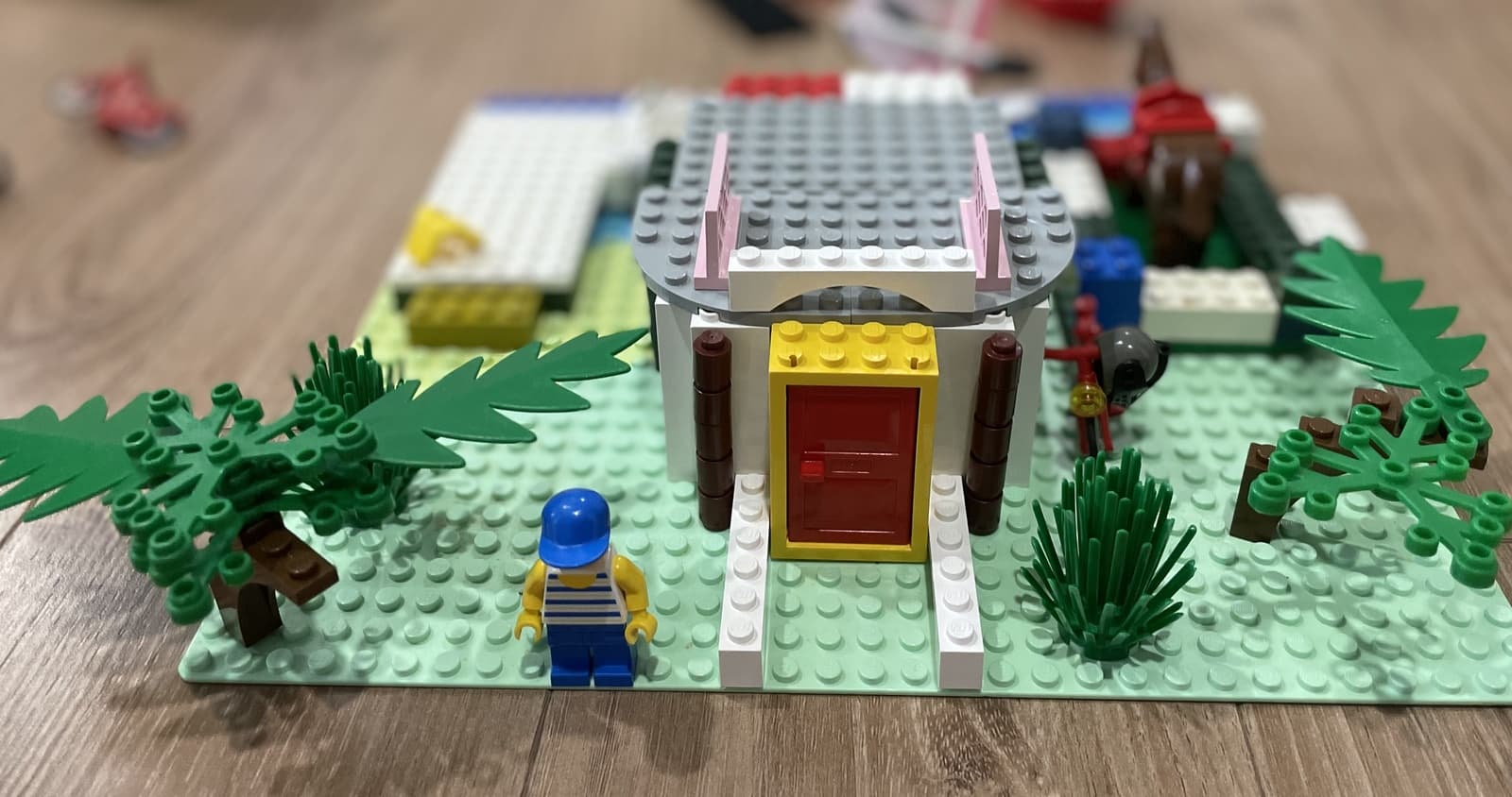 A pile of mixed LEGO bricks on a kitchen table, mid-build, with a half-finished tower and scattered wheels