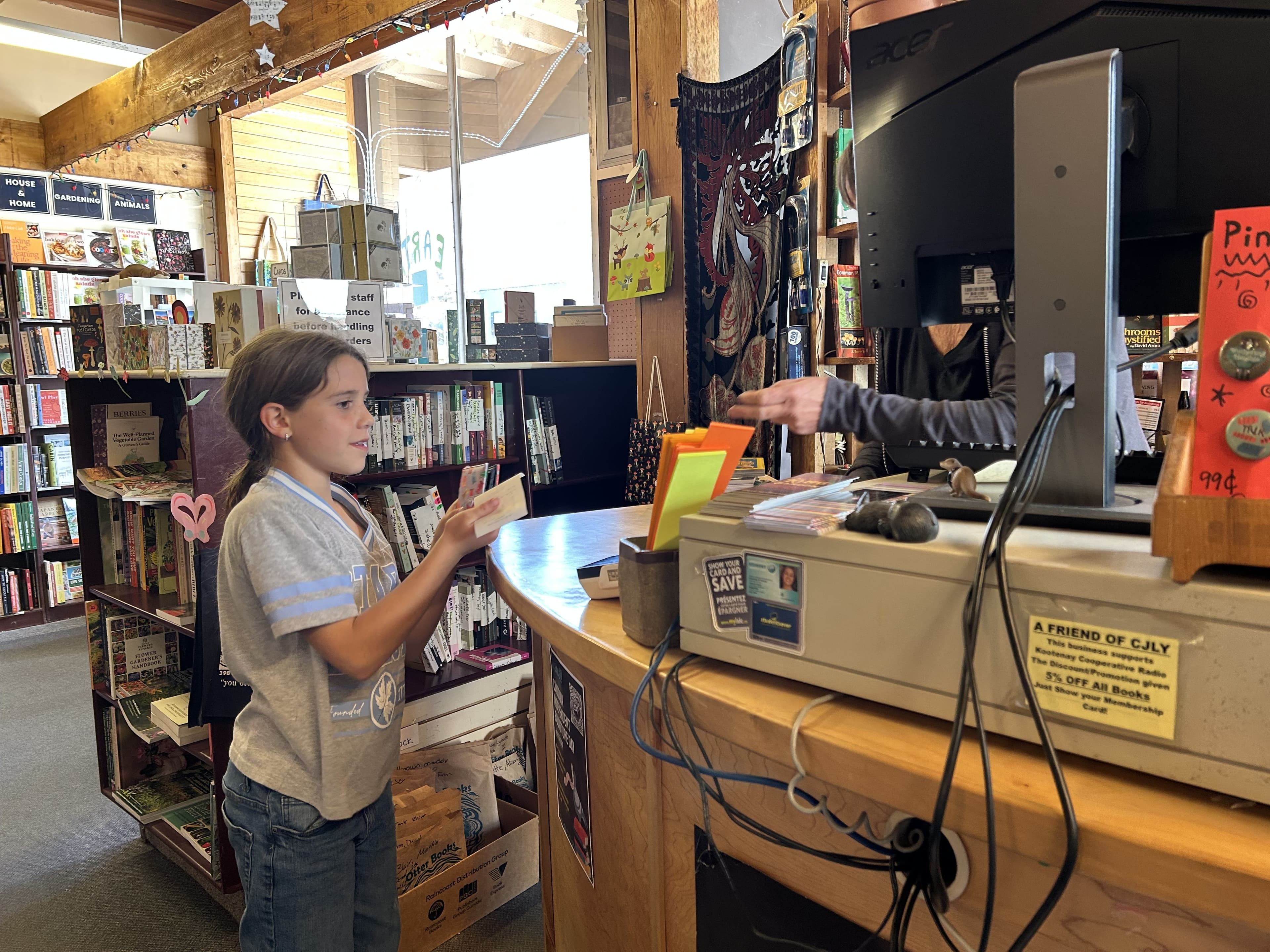 Julia at a bookstore counter buying a book on her own, handling the transaction independently