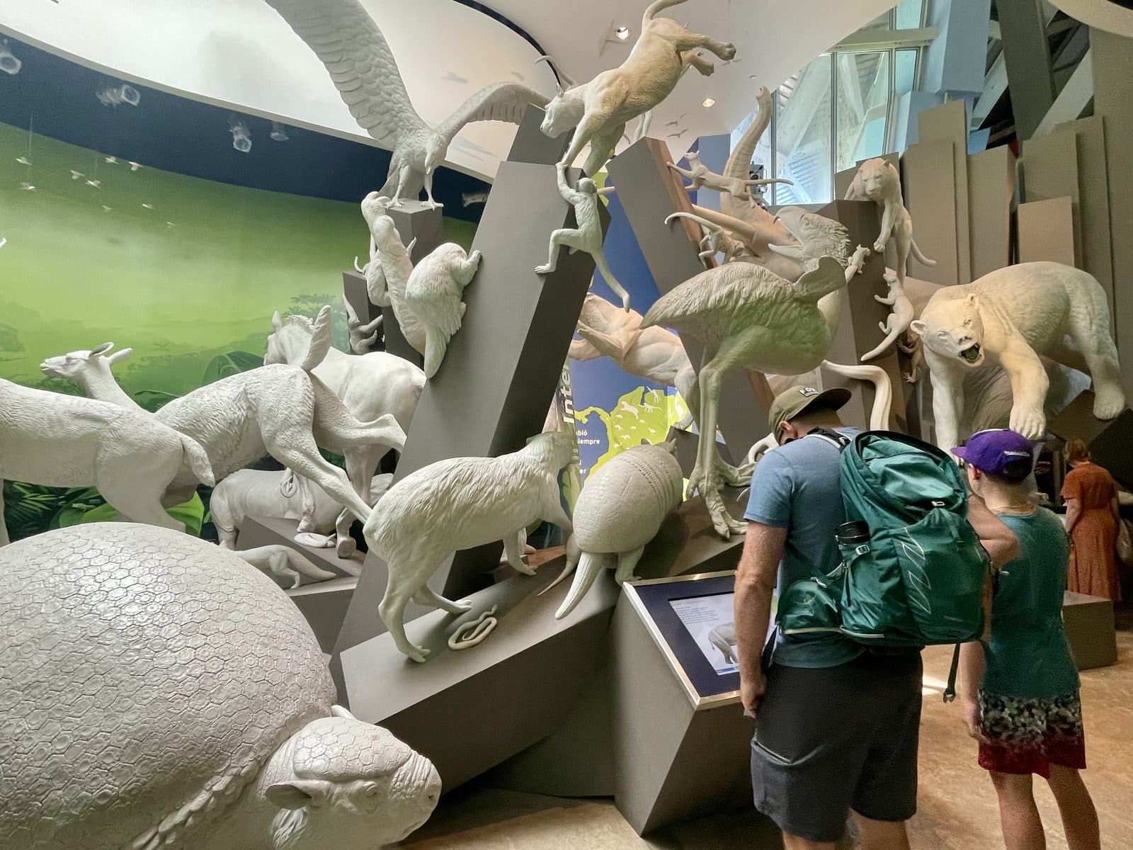 Family exploring a natural history museum exhibit with towering animal sculptures, discovering together