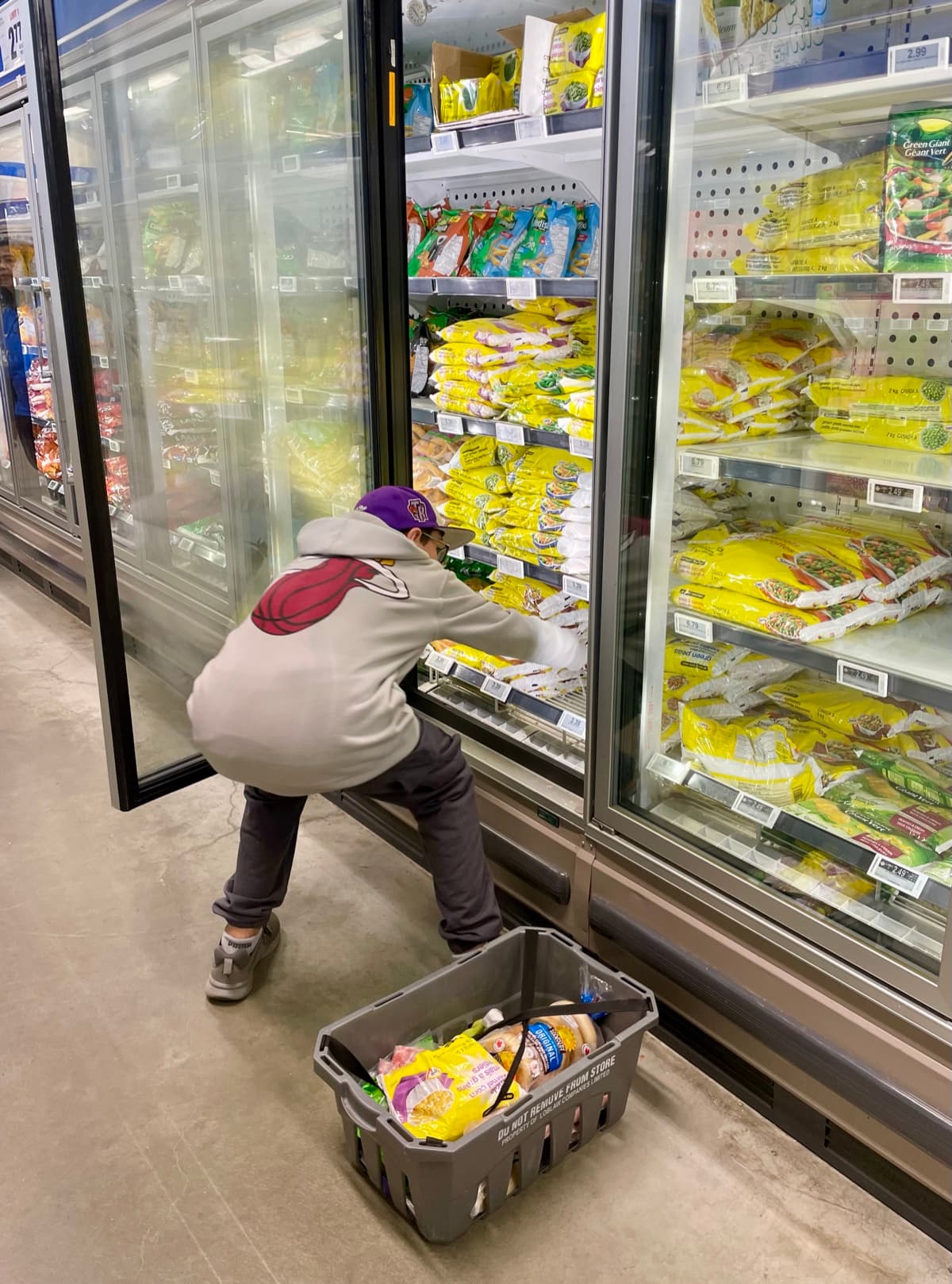 My son crouching at the grocery store freezer, picking items and comparing options on his own