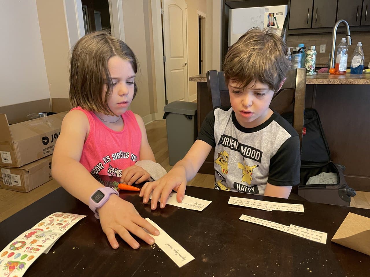 Two kids working through a hands-on language activity together at the table, sorting strips of paper