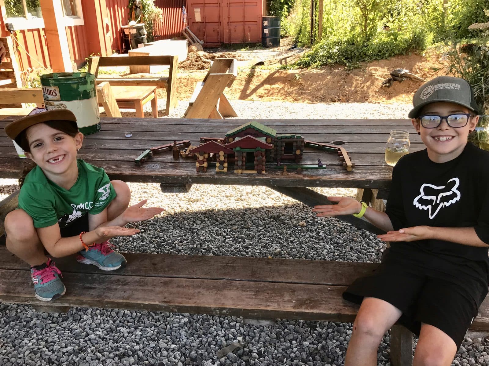 Zach and Julia proudly showing off a Lincoln Log village they built together, hands-on learning at its best