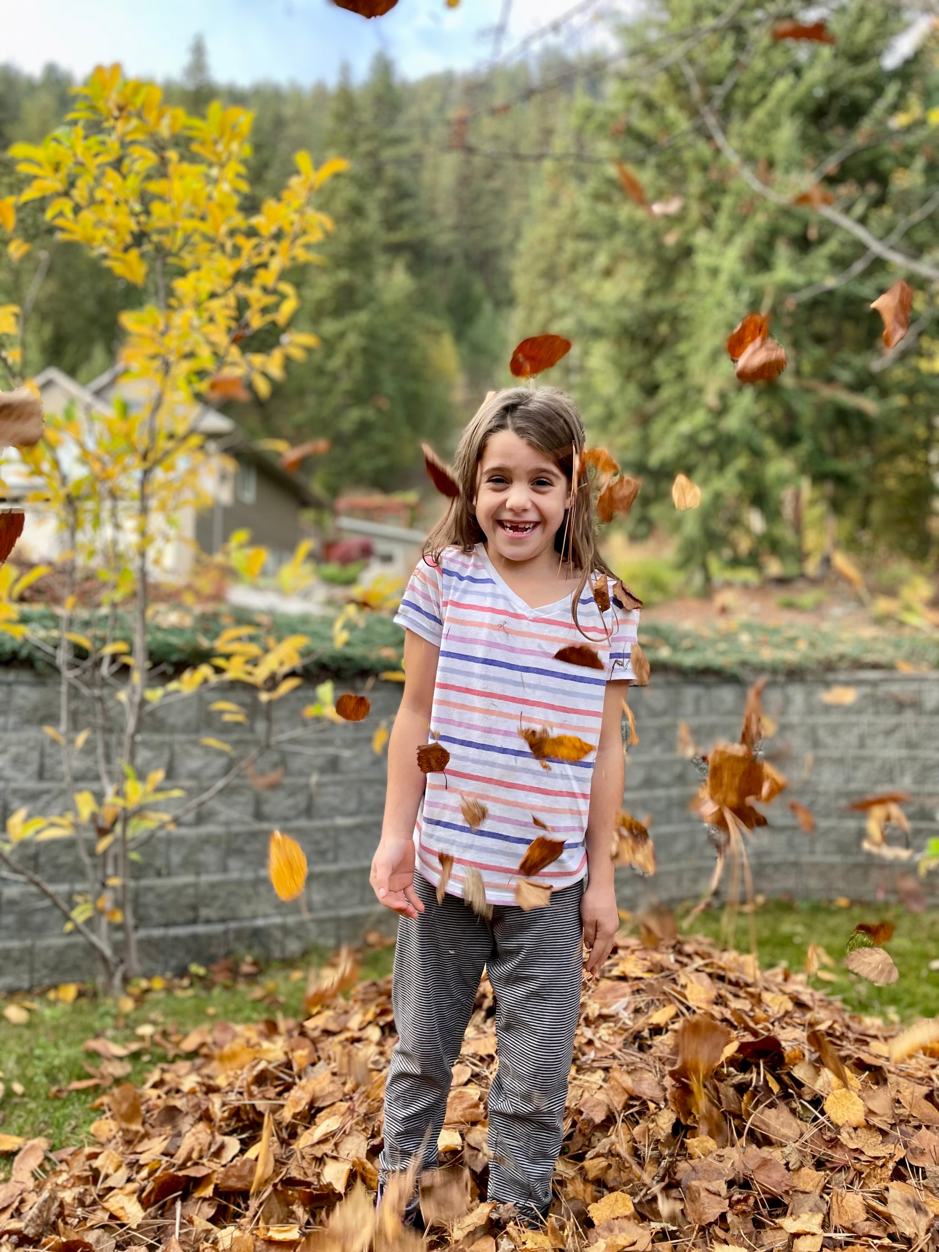 Child laughing joyfully in a shower of falling autumn leaves