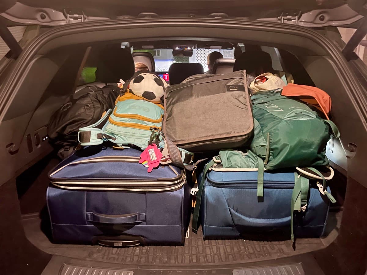 Car trunk packed full of suitcases, bags, and a soccer ball, ready for seven months on the road