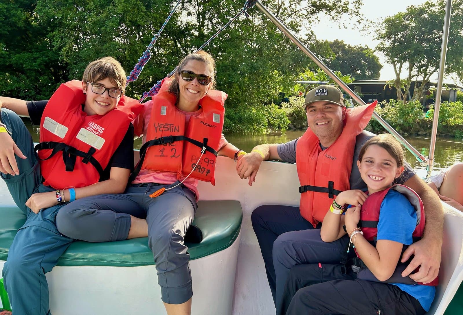 The whole family together on a boat: both kids, mom, and dad all smiling in life vests