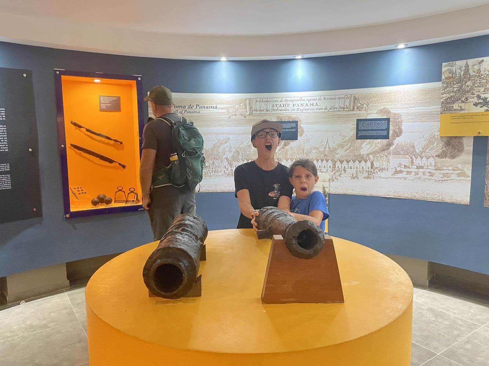 Two kids posing with old cannons at a Panama colonial history museum, mock-shouting next to the exhibit, the kind of museum visit kids actually remember