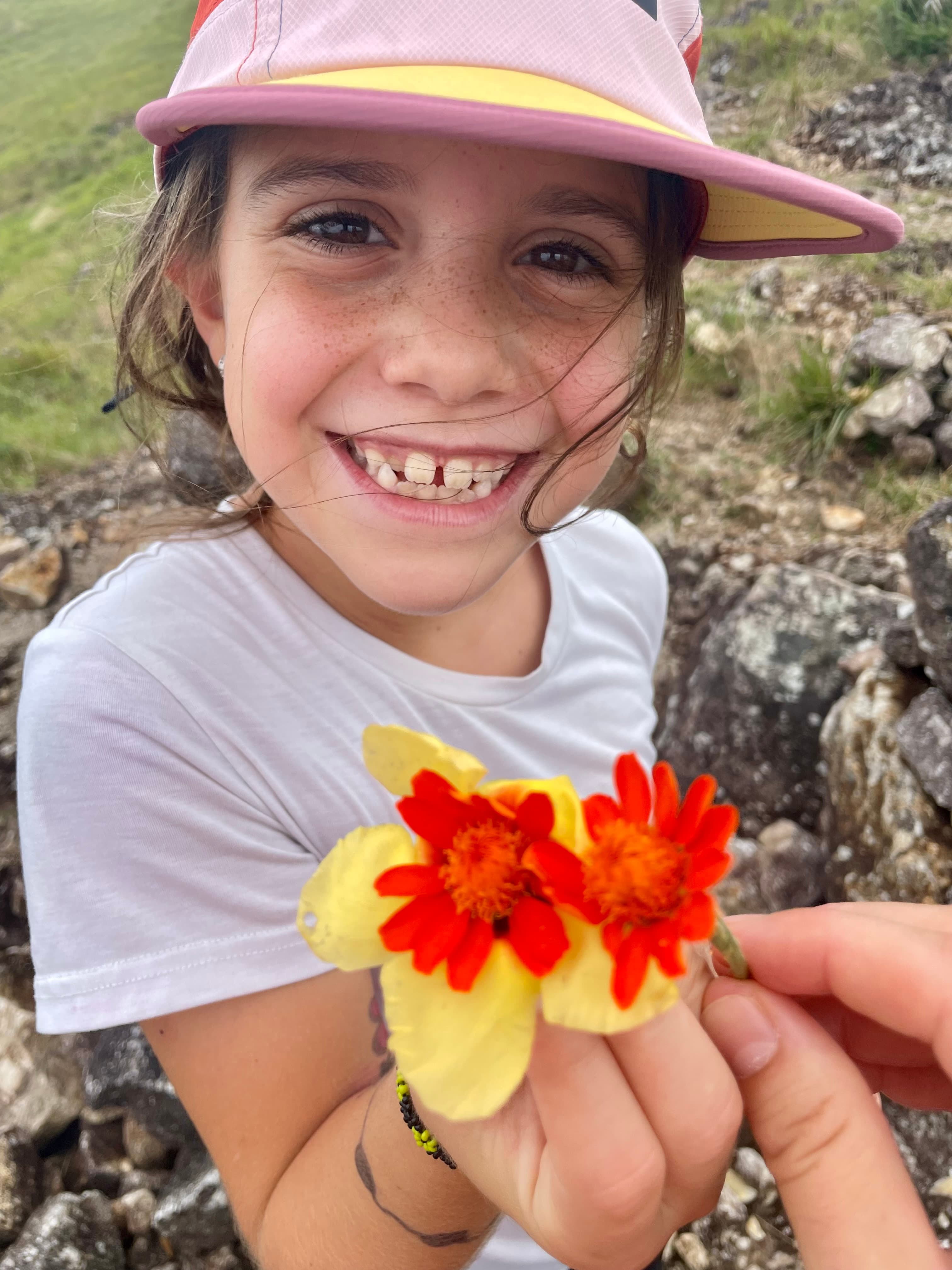 Girl beaming with pride holding wildflowers she collected on a hike