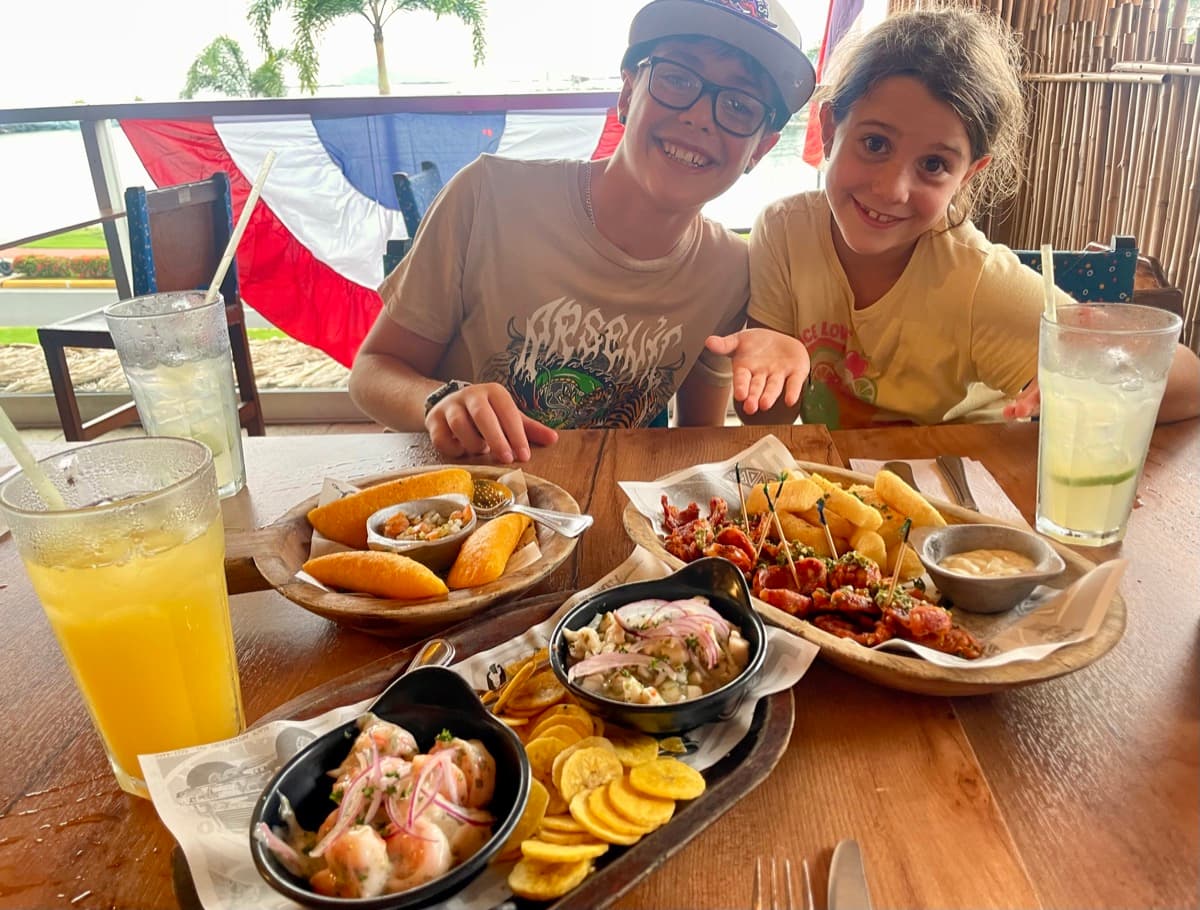 My son and daughter smiling together at a restaurant with local food spread across the table