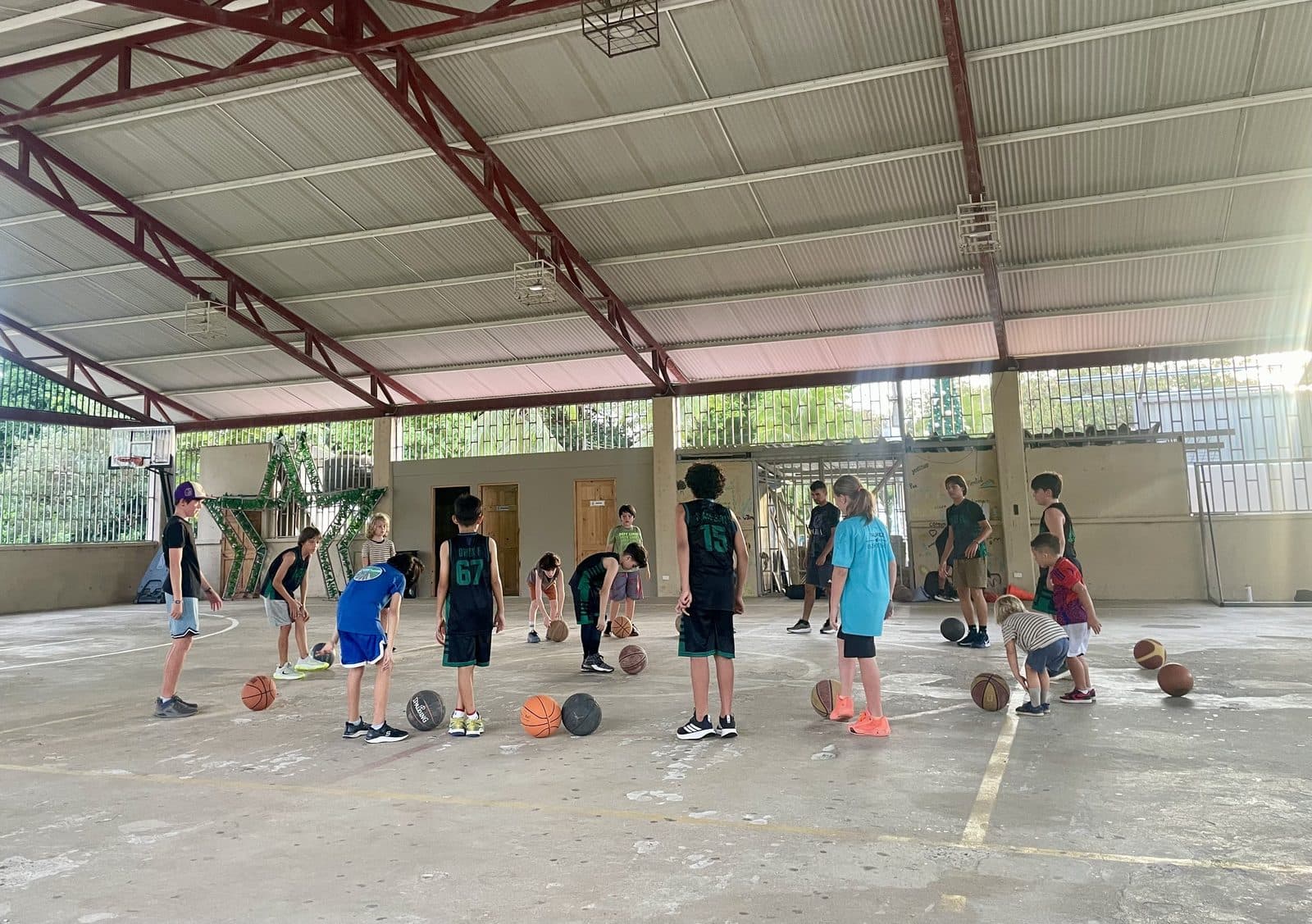 Kids playing basketball together at a covered court in Costa Rica, homeschool socialization in action