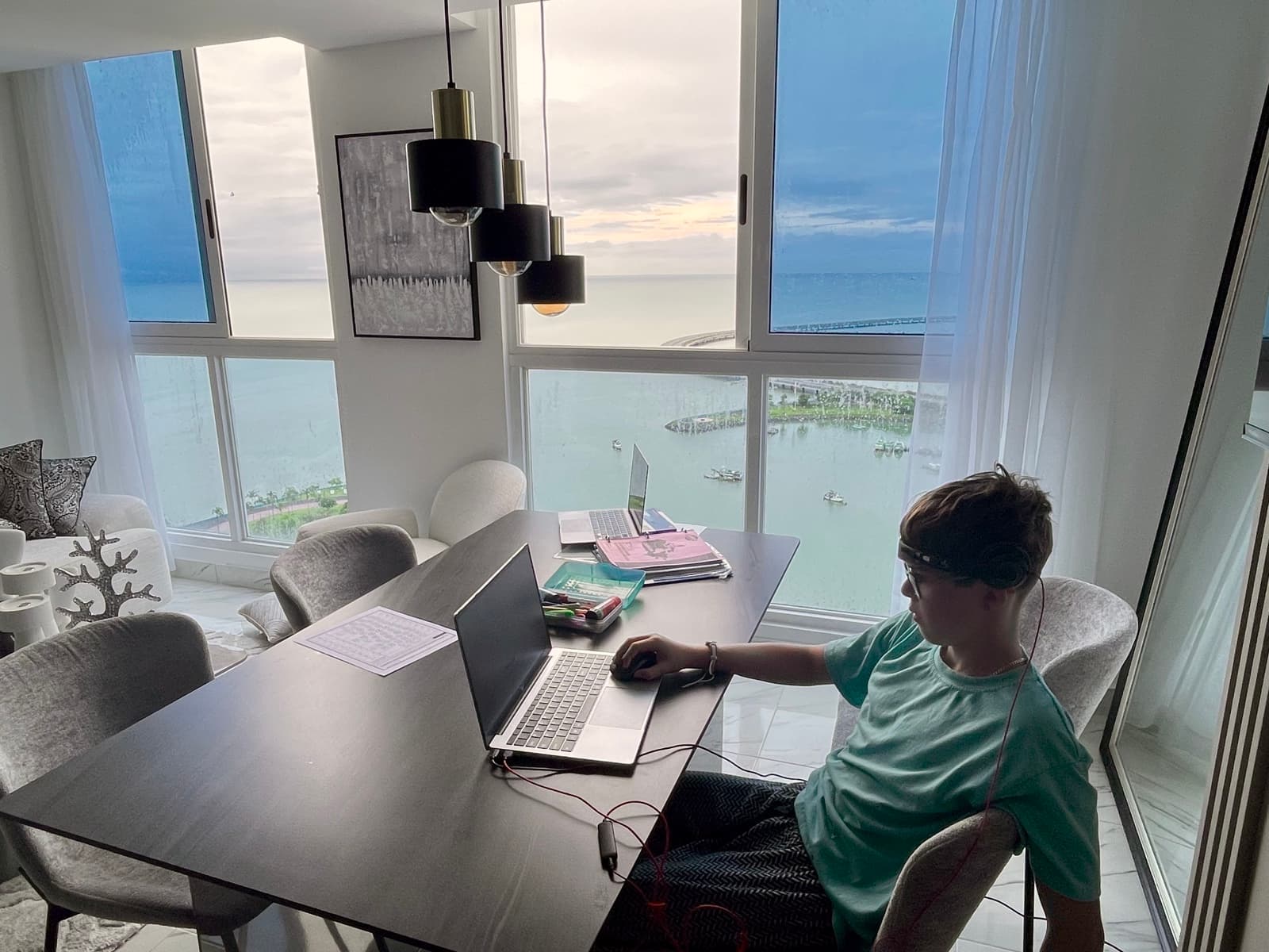 My son working on his laptop at a desk overlooking the ocean through floor-to-ceiling windows